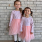 Two young girls in matching pink floral tulle dresses