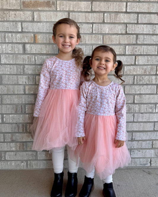 Two young girls in matching pink floral tulle dresses